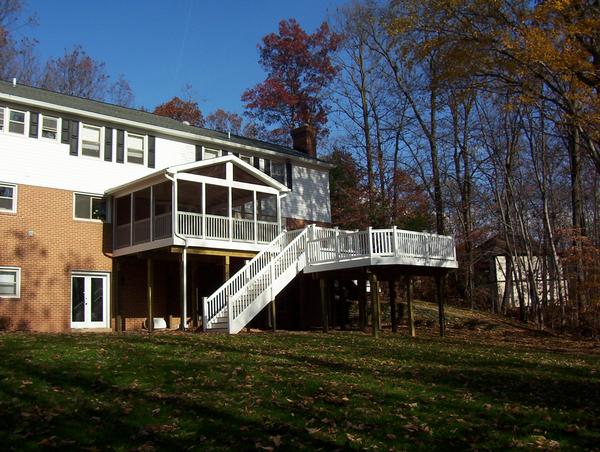 This is an image of a composite screen room with white composite railings and balusters.  The deck is multi-level with a composite white wrapped set of steps.